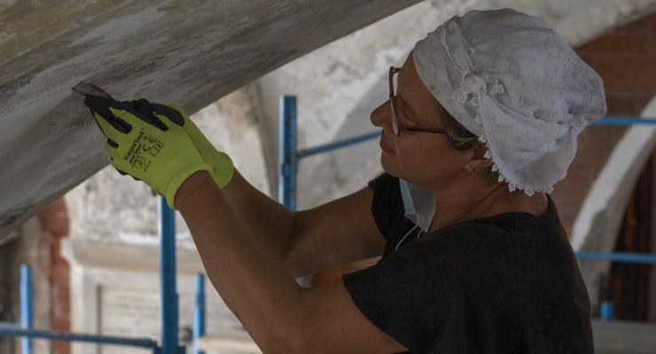 Una restauratrice lavora al descialbo della Galleria AB ponente inferiore, in prossimità della cripta del Famedio